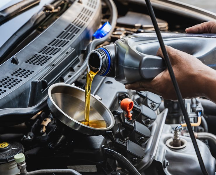 Car,Mechanic,Pouring,Engine,Oil,Into,Vehicle,During,Doing,Car Car mechanic pouring engine oil into vehicle during doing car maintenance in garage